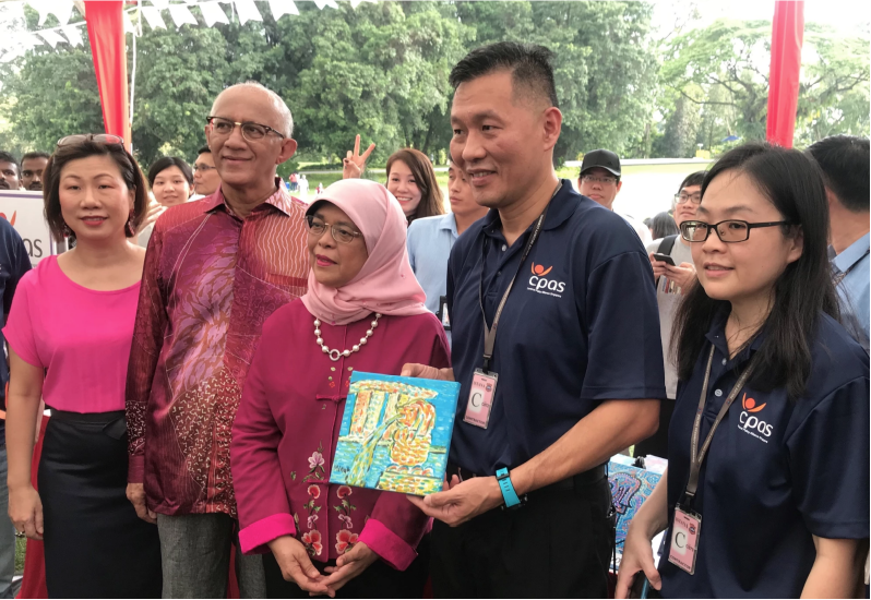 Picture shows President Halimah Yacob, her husband, and SG Enable CEO, Ms Ku Geok Boon, with i'mable Gift Market partner, Cerebral Palsy Alliance Singapore (CPAS), featuring an artwork by one of CPAS's members.